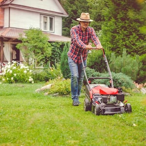 Man wearing a hat pushing a lawn mower