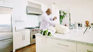 Man in the kitchen taking groceries out of canvas bags