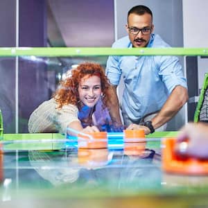 Group of friends having fun playing air hockey