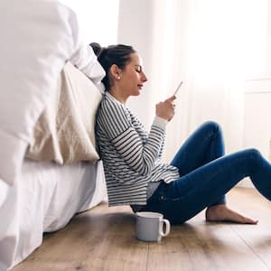 woman sitting on the floor looking up something on her phone    