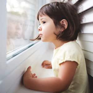 A toddler girl looking out the window