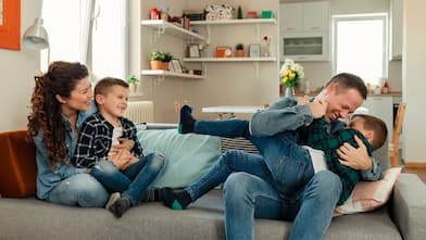 family laughing/ playing on couch