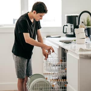 A teeneger putting dishes in dishwasher machine