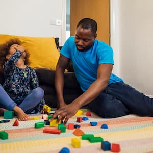 A father and his daughter playing with blocks on a rug