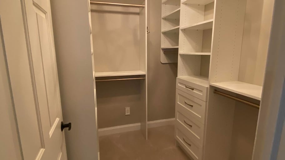 An empty walk-in closet with a hanging chandelier