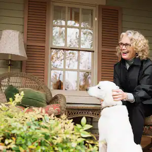 A woman sitting on porch rocking chair with dog