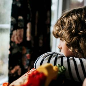 A child looks out a window at a storm