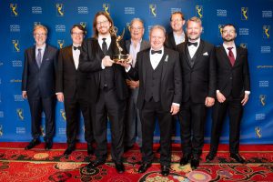 men in suits from the WOFF Working group, one holding an Emmy 