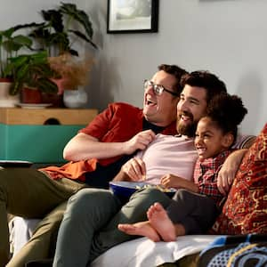 Fathers with their daughter watching tv and laughing