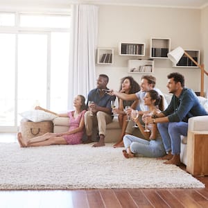 Group of friends relaxing at home watching TV together