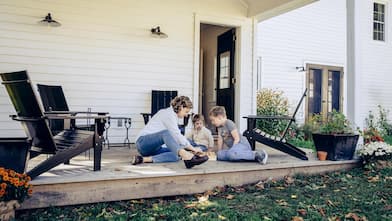 A mother with her kids playing chess on a porch