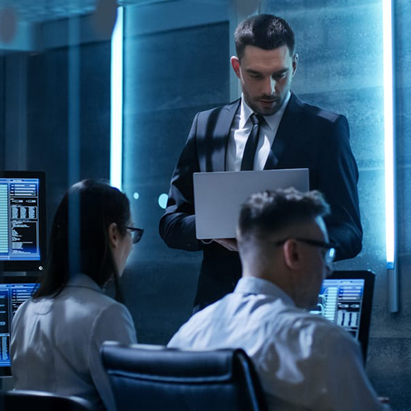 Photo of a person holding a clipboard in a room full of people on computers wearing headsets