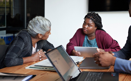 A businesswoman has a discussion with a blind colleague in a board meeting