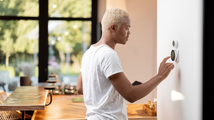 A man changing the temperature via a thermostat