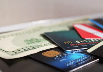 A pile of credit cards next a U.S. 100 dollar bill.