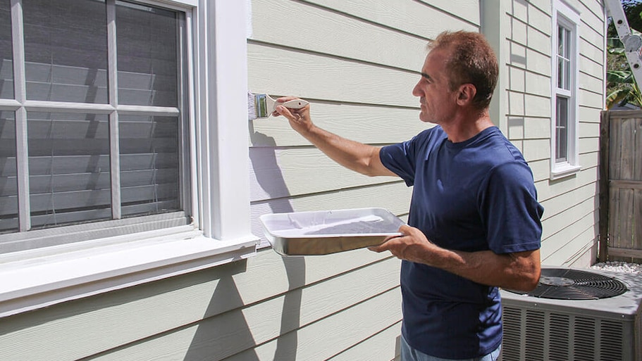 Man painting house siding