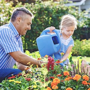 Grandpa and granddaughter waters flowers with a watering can 