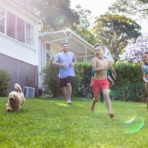 Family running in the yard with their pet