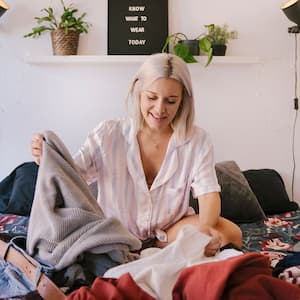 blonde woman choosing clothes on a bed