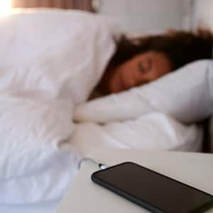 A woman sleeping while her phone is charging