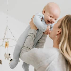 Mother throwing baby boy in air in bedroom