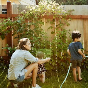 Family watering yard by fence