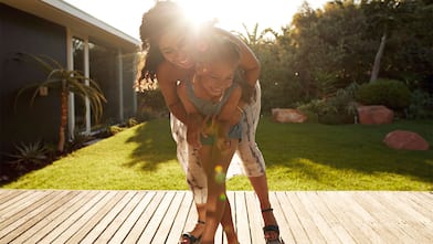 A mother and daughter hugging on backyard deck