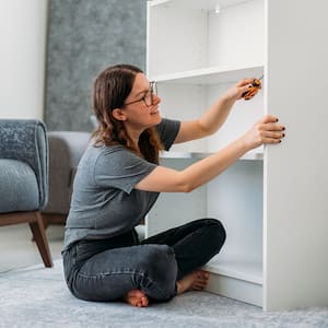 woman disassembling a wooden cabinet at home