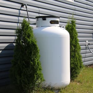 propane tank between two bushes along side of house