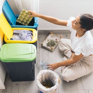 woman recycling plastic bottle in garbage bin