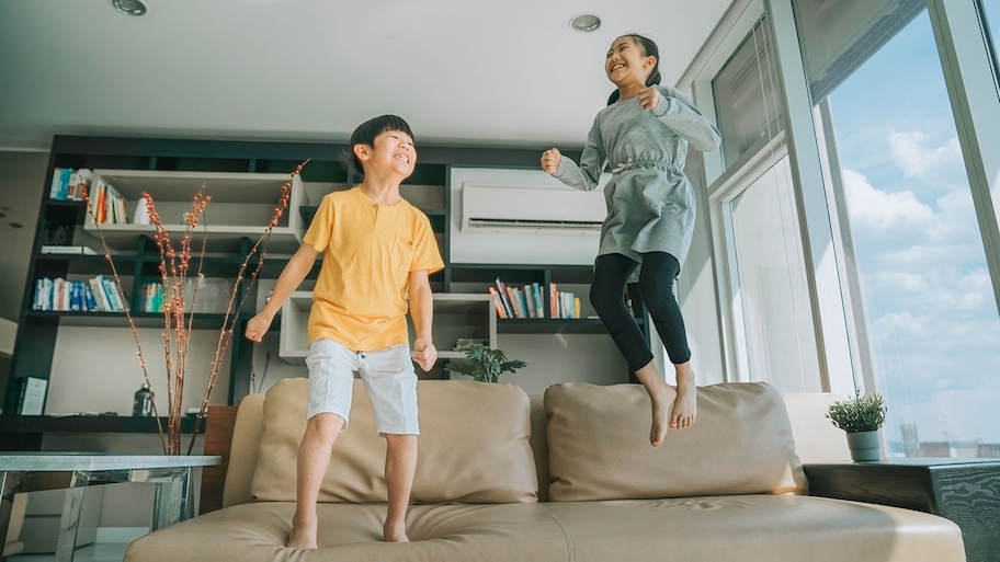 Boy and girl at home jumping on the couch