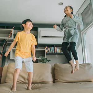 Boy and girl at home jumping on the couch