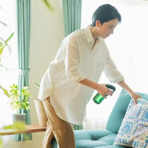 A woman disinfecting sofa pillows