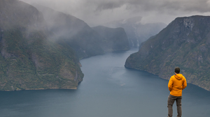 Turgåer i gul jakke som kikker utover Aurlandsfjorden i Flåm.