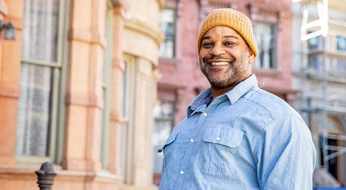 A male Veteran standing outside and smiling.