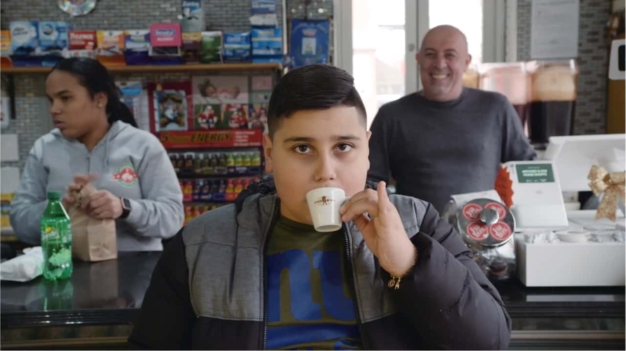 Young boy sipping tiny cup with pinky finger up