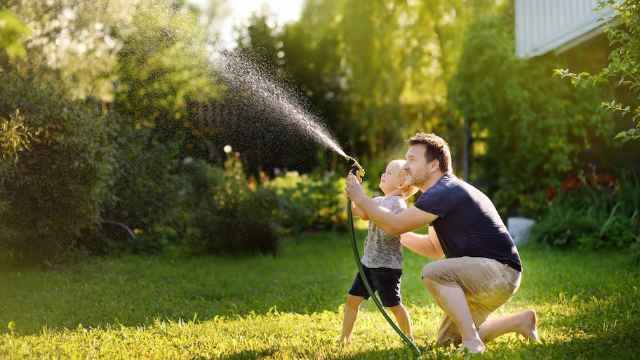  A father with his son watering the lawn with a hose