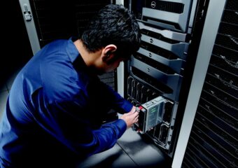 Man in blue shirt pulls a blade server out of server rack.