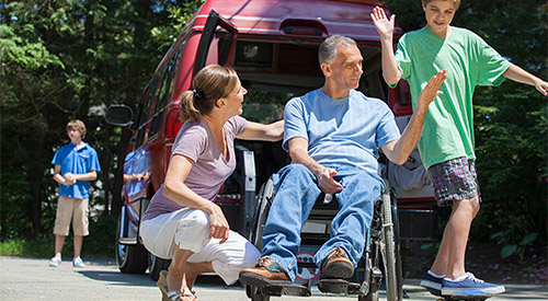 A Veteran in a wheelchair outside with his family