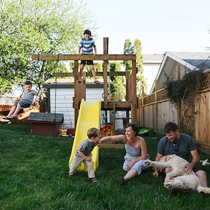 Family playing on a backyard playground and swing set