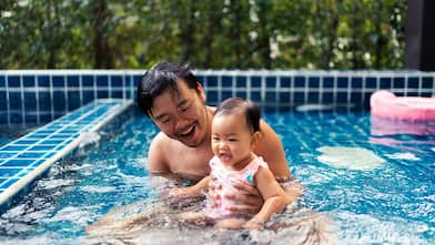 Father and toddler daughter playing in the swimming pool