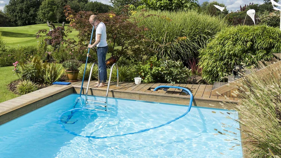 Man cleaning backyard pool wooden deck