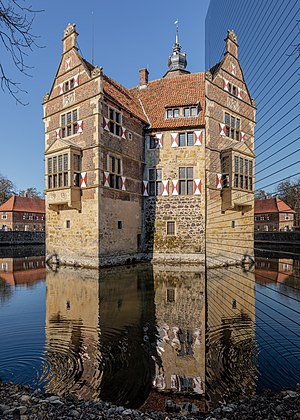 Casteddu de Vischering (cun riflessos in s'abba e in un'ispricu in su pannellu de sas informatziones) in Lüdinghausen, Renània de su Norte-Westfàlia, Germània