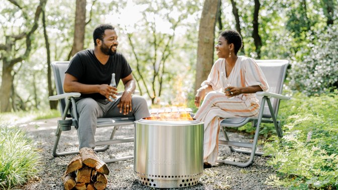 Two people sitting around a portable fire pit