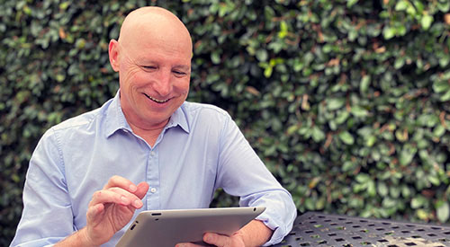 A Veteran sitting at a table outside on his computer.