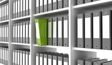 Gray binders in a bookcase with one green binder pulled out