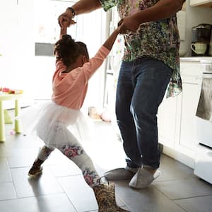 A father and daughter play in a kitchen