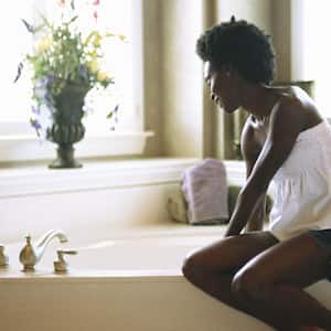 A woman sitting on edge of bathtub