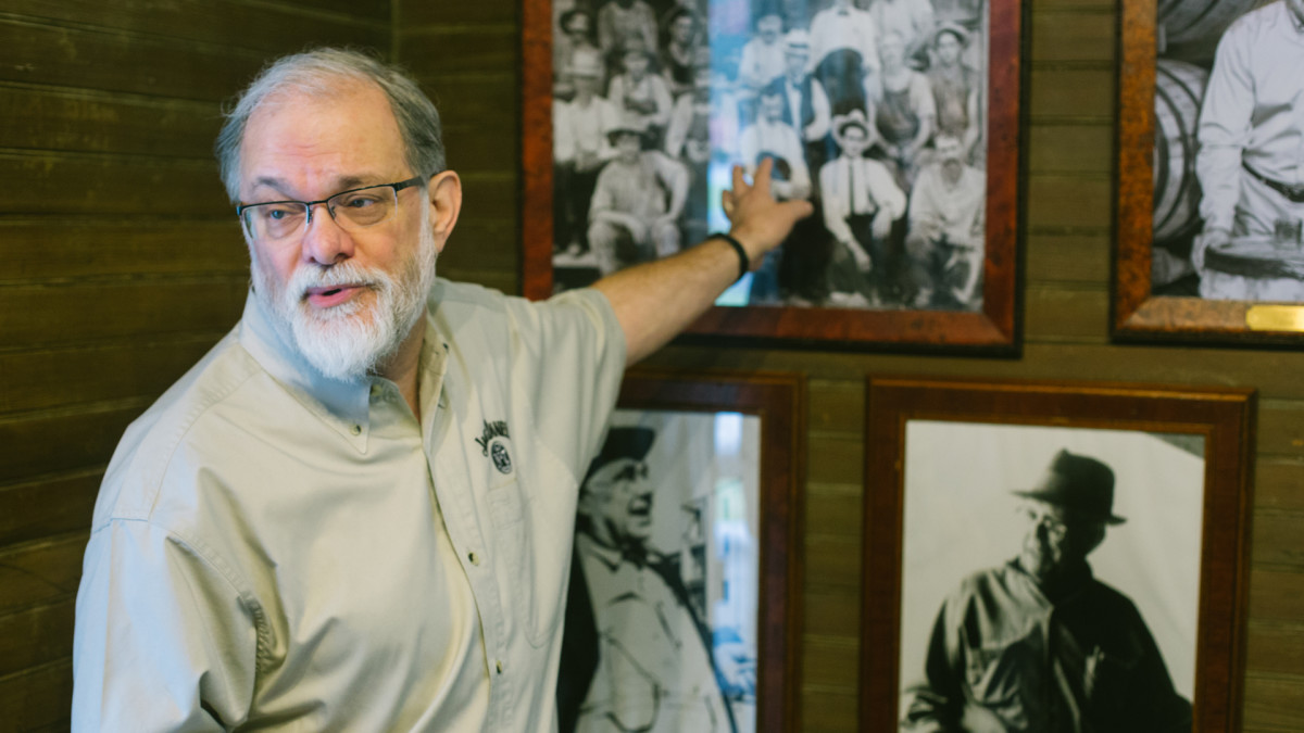 Jack Daniel's company historian speaking in the old office of company founder Daniel on the grounds of the Jack Daniel's distillery, pointing to the photograph showing Daniels and Green, 2018. 