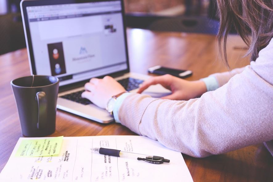 Woman working on a computer with notepad on desk